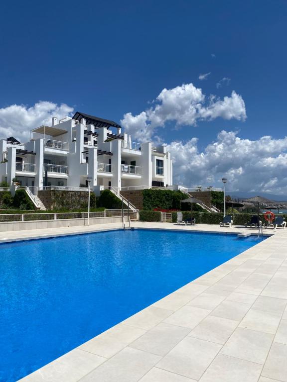 uma piscina em frente a um grande edifício branco em Sunshine beach front complex, WiFi, modern em Casares