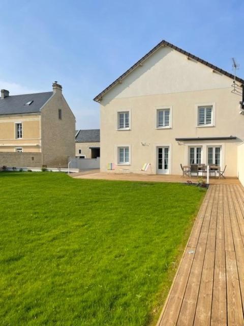 a large white house with a large grass yard at Maison au sein d’un corps de ferme. in Carpiquet