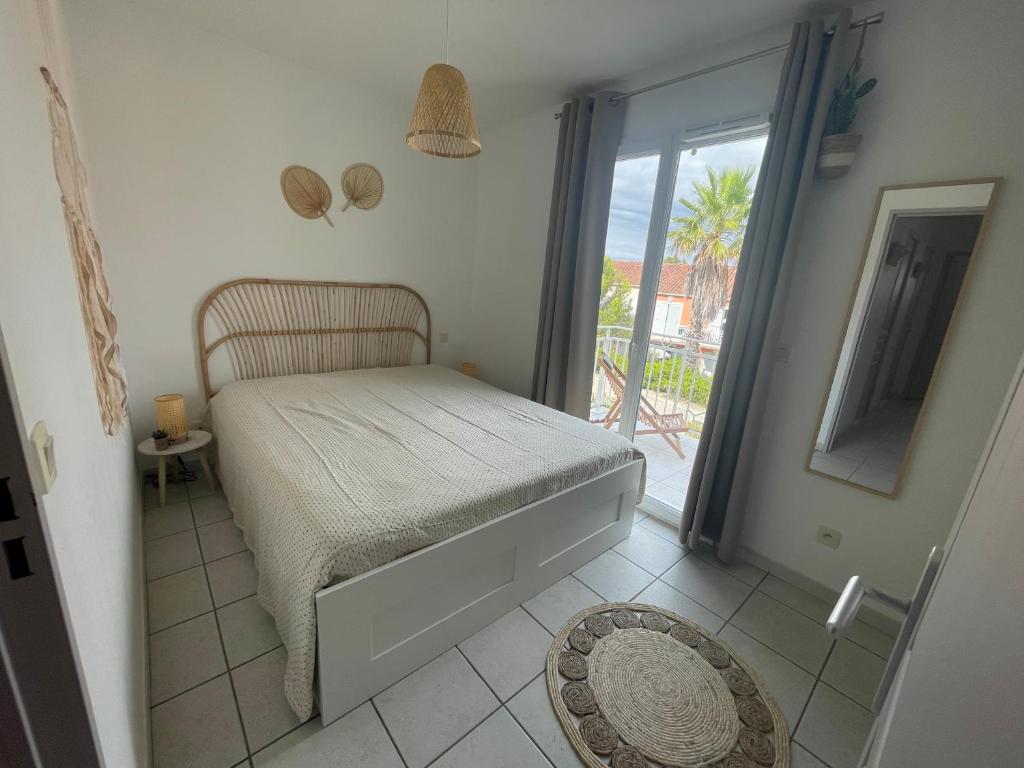 a small bedroom with a bed and a balcony at Superbe appartement 6pers avec piscine et jardin in Fréjus