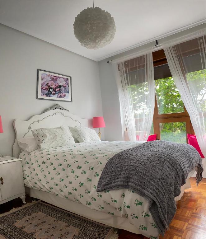 sypialnia z łóżkiem z białą narzutą i oknami w obiekcie Apartamento La Muralla parking gratis w mieście Burgos