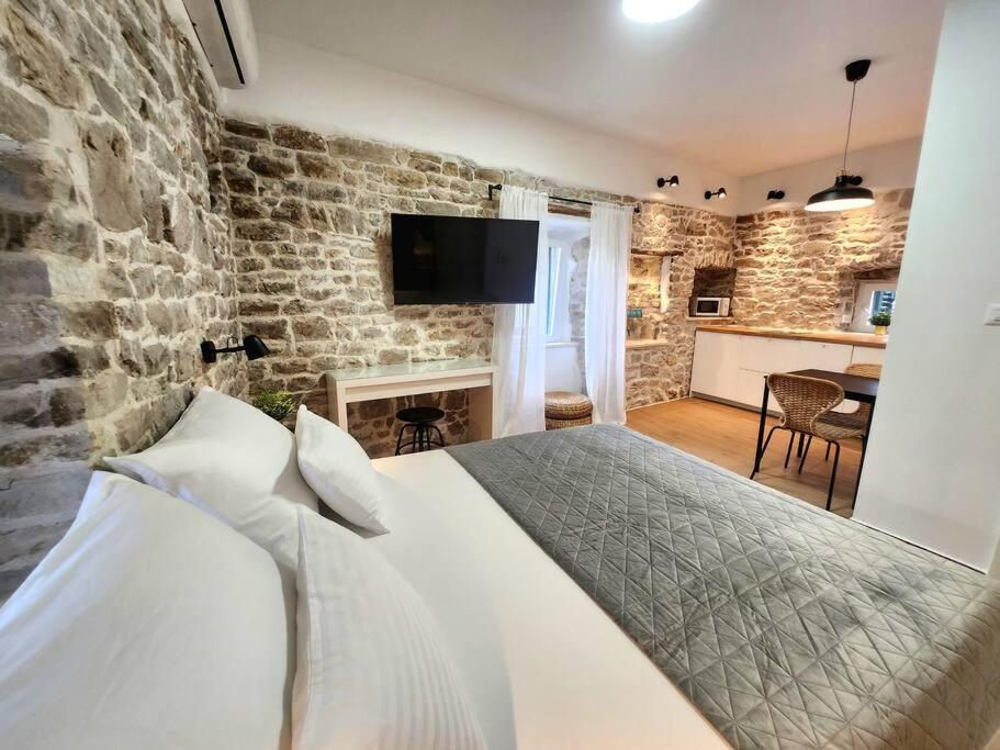 1 dormitorio con cama y pared de piedra en Mariani studio apartments old town, en Split