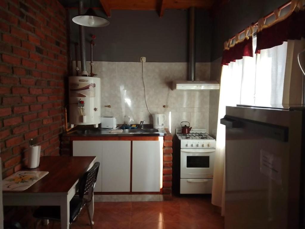 uma cozinha com um fogão branco e uma mesa em Departamentos alvear em Esquel