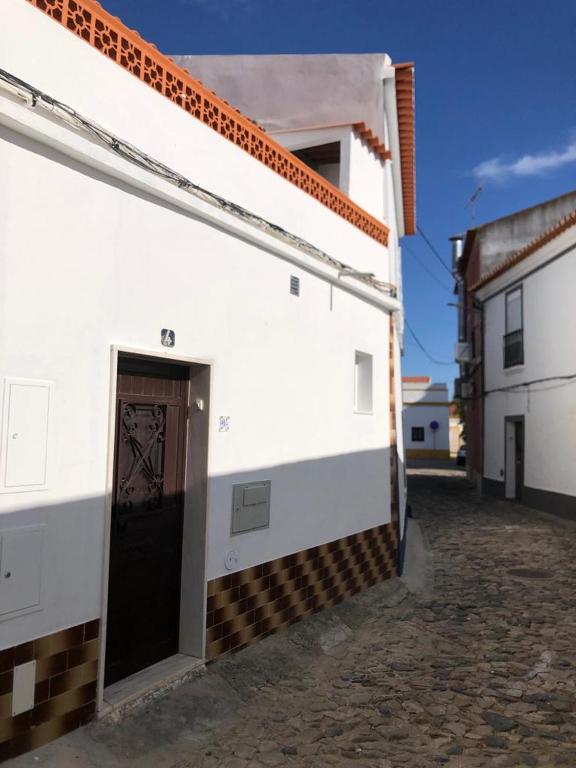 a white building with a door on the side of it at Casa Da Praça in São Pedro do Corval