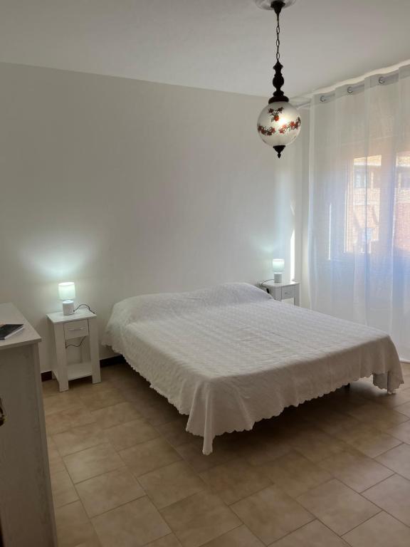 a white bedroom with a bed and a chandelier at Maison De Plage in Sabaudia