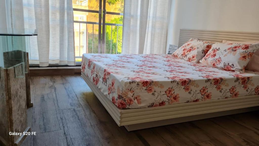 1 dormitorio con 1 cama con colcha de flores en Apartamento Sandy-Zona Sul en Río de Janeiro
