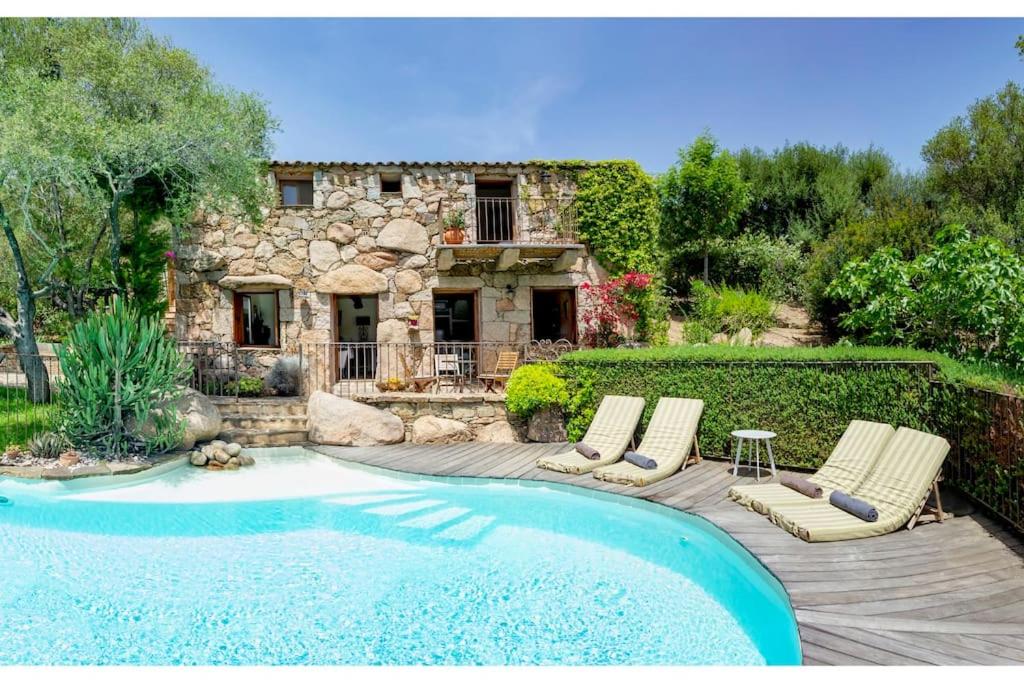 a swimming pool with two lounge chairs and a house at Les Lauriers Roses Palombaggia Porto-Vecchio in Porto-Vecchio