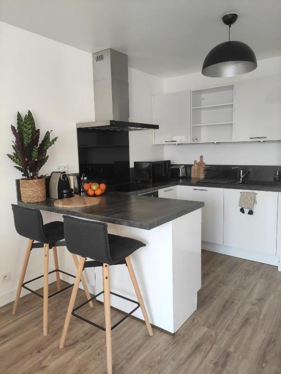 une cuisine avec des armoires blanches et une table avec des chaises dans l'établissement Calme et verdure à Poissy 50 m2 parking terrasse, à Poissy