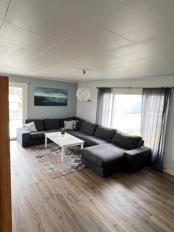 ein Wohnzimmer mit einem schwarzen Sofa und einem Tisch in der Unterkunft Hus sentralt i Lofoten in Leknes