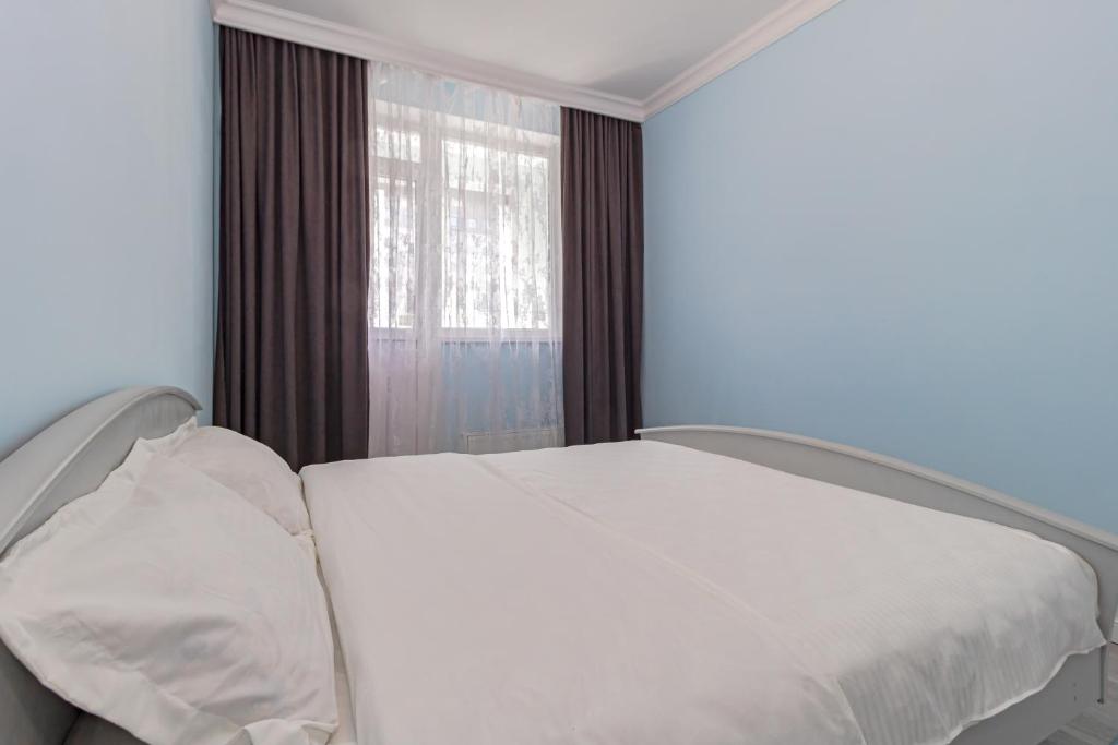 een wit bed in een kamer met een raam bij Korkem 4-313 Триумфальная Арка in Taldykolʼ