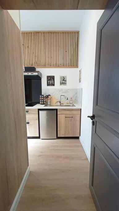eine offene Tür zu einer Küche mit einem Waschbecken in der Unterkunft Le Raffiné in Millau