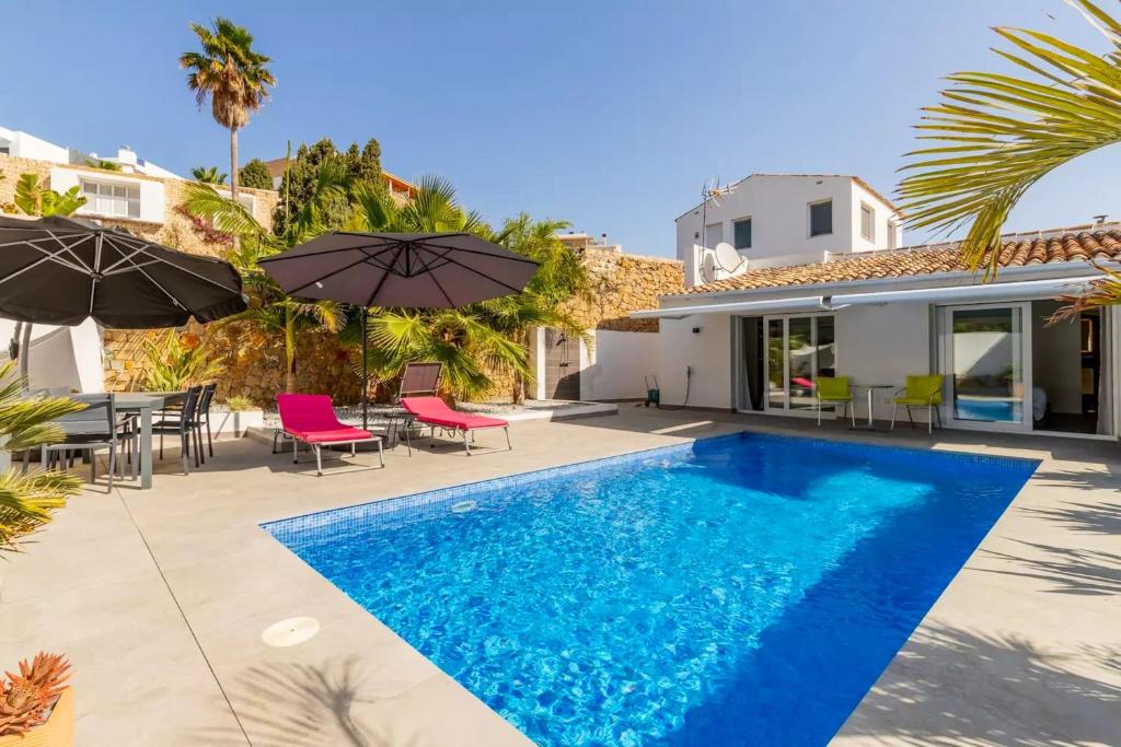 a villa with a swimming pool with chairs and umbrellas at Mediterranean villa in Calpe with private pool. in Calpe