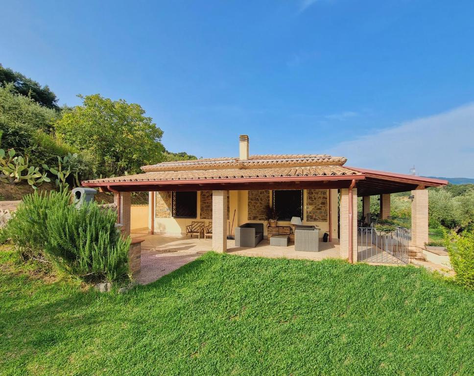 ein kleines Haus mit einer Terrasse und einem Grasfeld in der Unterkunft VILLA in 8 ettari di campagna, a 20' dal mare in Casa Piccirillo