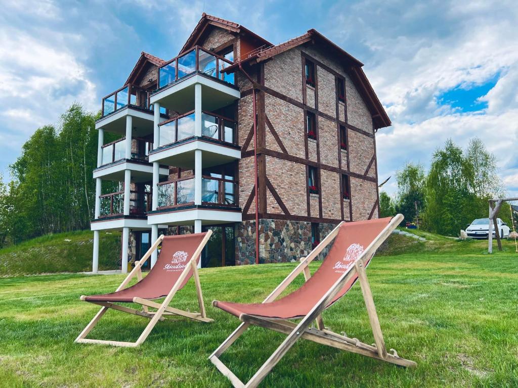 twee ligstoelen voor een gebouw bij Skoczybruzda Apartamenty in Chmielno