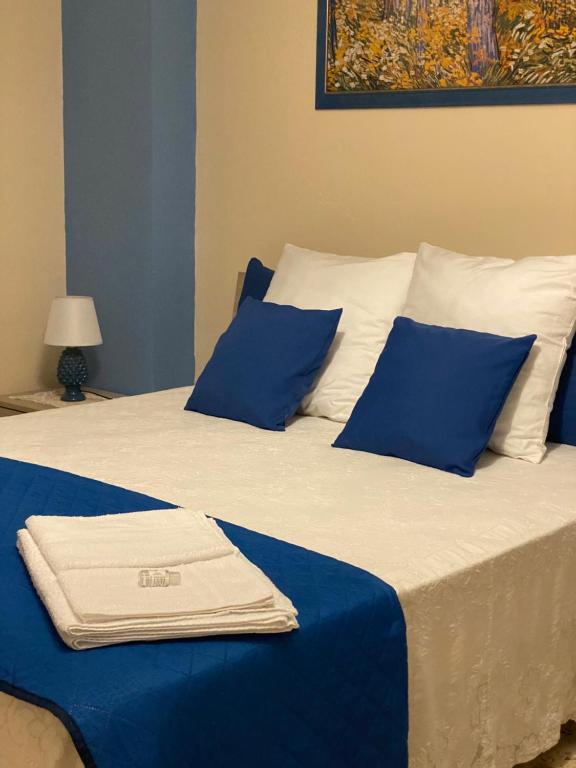 ein Bett mit blauen und weißen Kissen und einem Handtuch darauf in der Unterkunft Casa Dominique in Cefalú