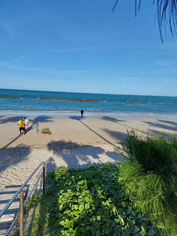 塔曼達雷的住宿－Marinas Tamandaré Flat，沙滩上的人在沙滩上和大海上散步