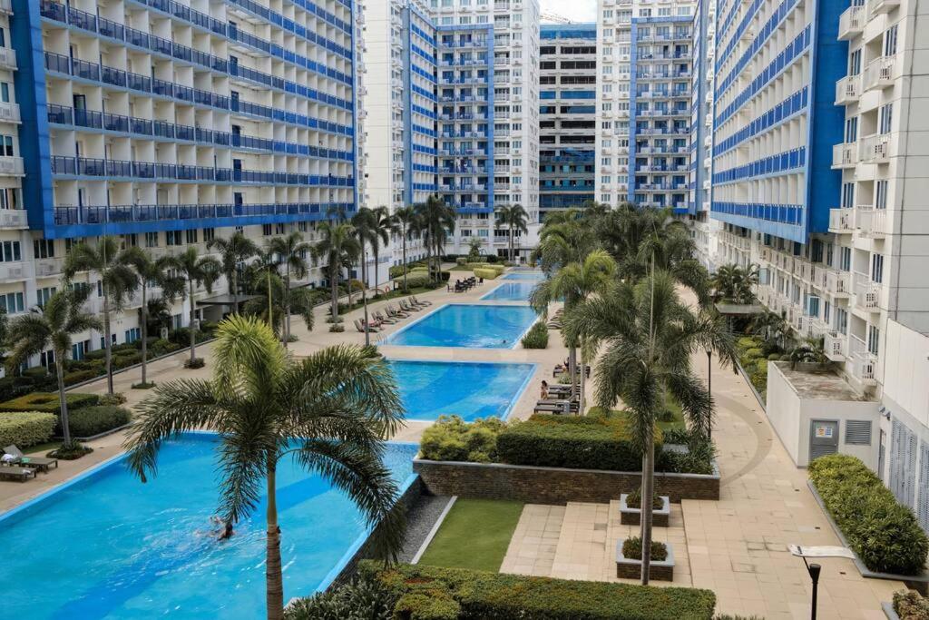 Vista al mar de una piscina con palmeras y edificios en Sea Residences - Classy Unit Near Mall of Asia, Arena, Ayala, Ikea, Okada, SMX, PITX, Airport en Manila