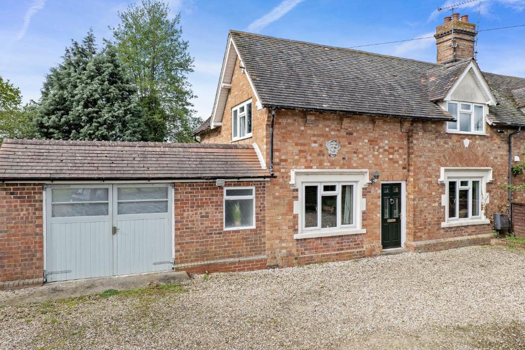 a brick house with a white garage at Wheelbarrow Cottage in Bengeworth
