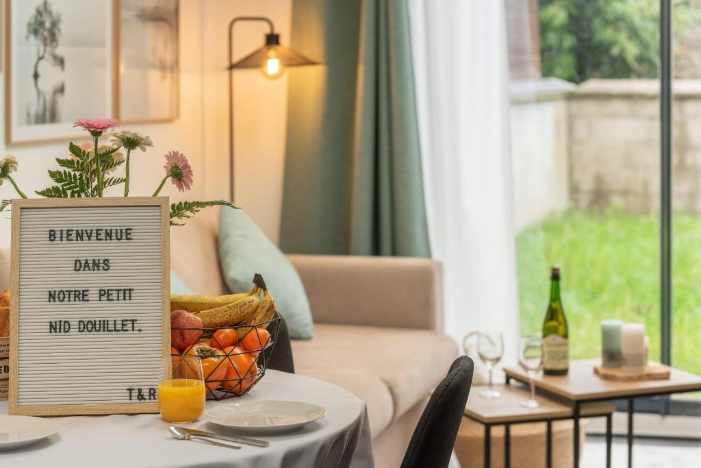 un tavolo con un cartello sopra con un cesto di frutta di Le Nid Douillet : Superbe Appartement + Jardin privatif a Rouen