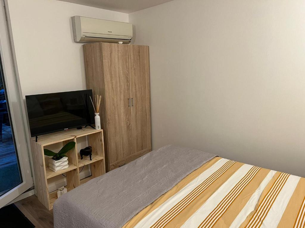 a bedroom with a bed and a tv and a cabinet at Abrilove in Castres