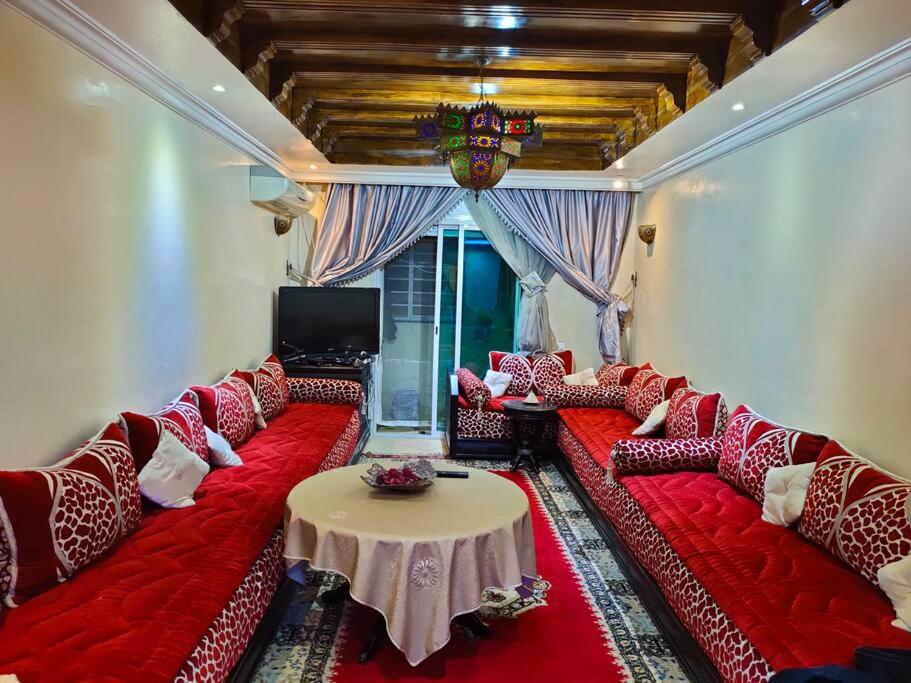 ein Wohnzimmer mit roten Sofas und einem Tisch in der Unterkunft Appartement Meublé Quartier Hassan Rabat in Rabat