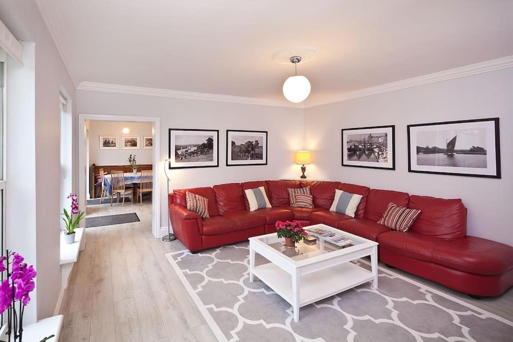 a living room with a red couch and a table at River Views, Beccles - HOT TUB + Norfolk Broads in Beccles