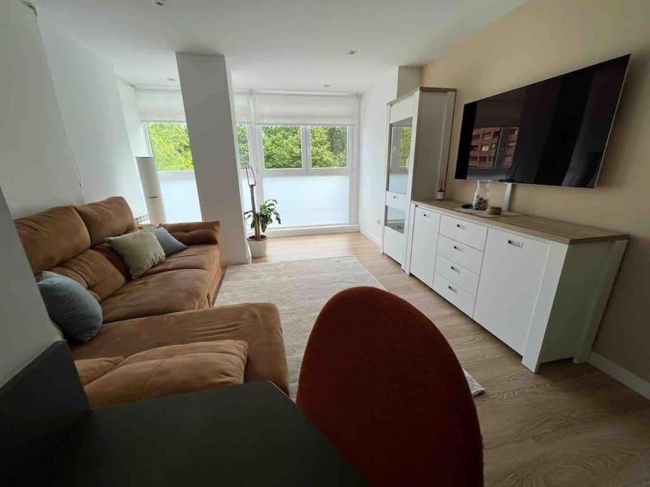 a living room with a couch and a flat screen tv at Precioso apartamento recién reformado in Gijón