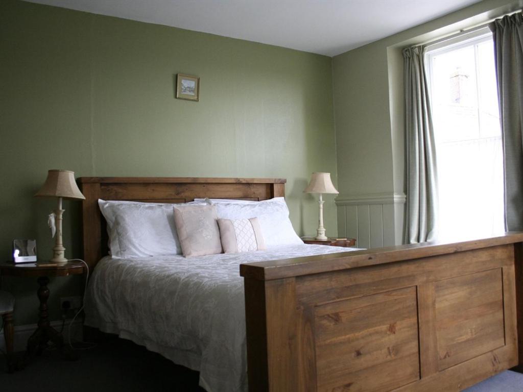 a bedroom with a bed with white pillows and a window at The Pack Horse Inn in South Brent