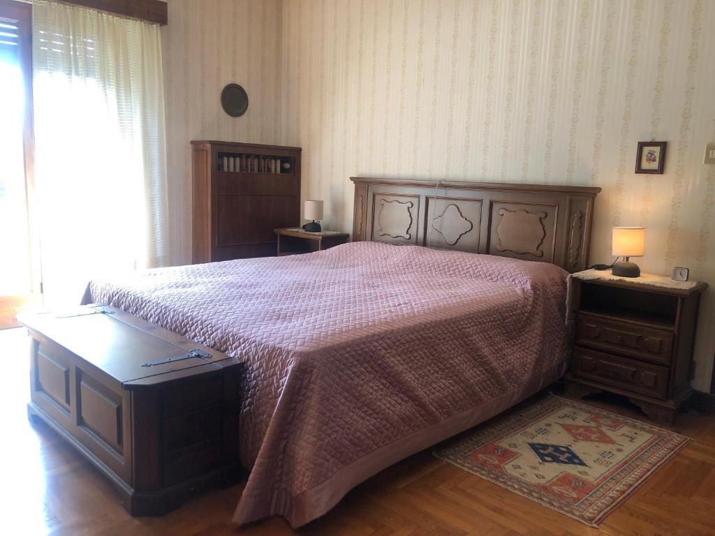 a bedroom with a large bed with a pink bedspread at Appartamento con vista panoramica in Saint Vincent