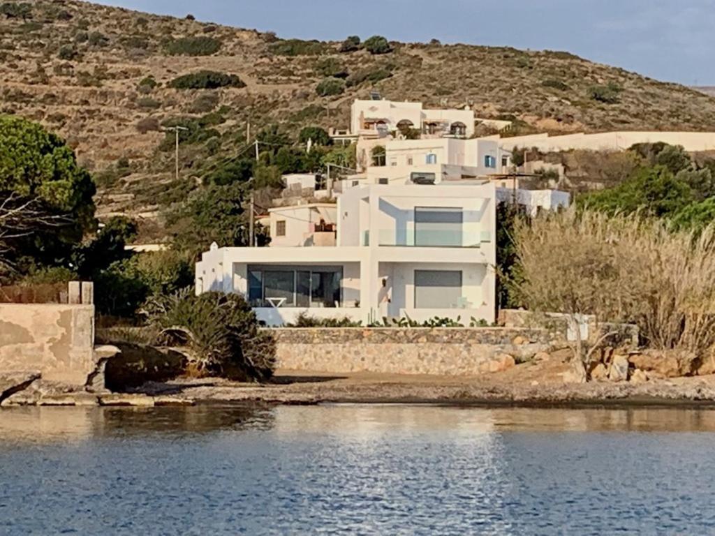 a large white house on a hill next to the water at Kokkali Beachfront Villa Leros in Gourna