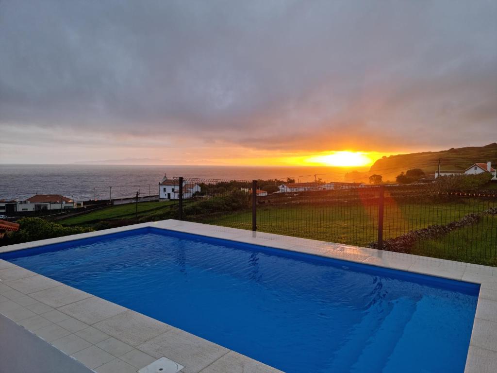 a swimming pool with the sunset in the background at Casa da Torre in Angra do Heroísmo