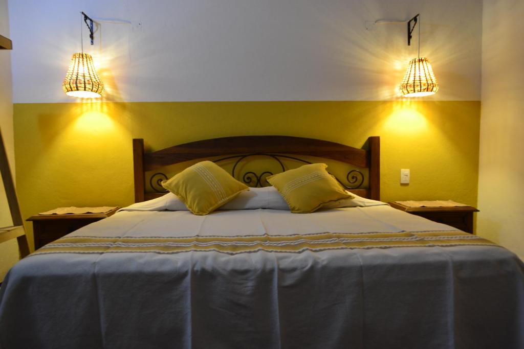 um quarto com uma cama com paredes amarelas e duas luzes em ¡Hermosa Estancia Centro de Oaxaca! em Oaxaca de Juárez