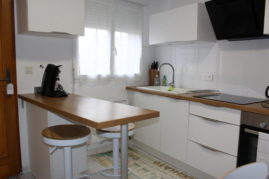 a kitchen with white cabinets and a wooden counter top at Tresor de Beaurains in Beaurains
