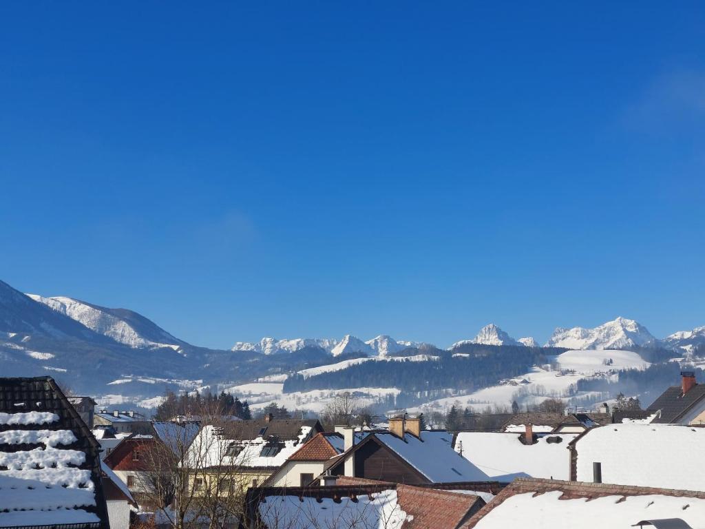 a town with snow covered roofs and mountains in the background at Haus Jezek in Windischgarsten