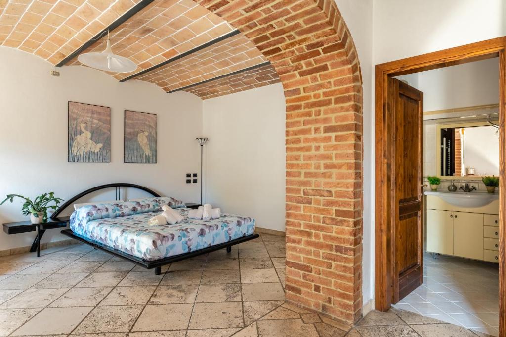 1 dormitorio con cama y pared de ladrillo en Le Volte ( Matrimoniale esclusiva più divani letto), en Gambassi Terme