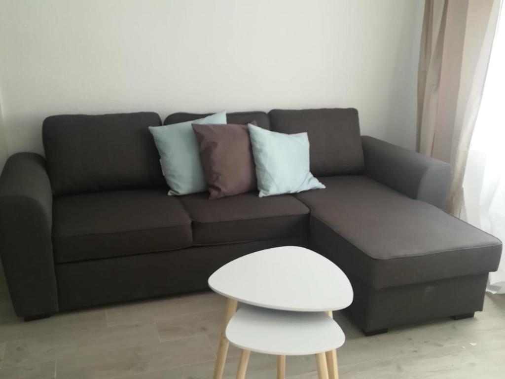 un canapé noir avec des coussins et un tabouret blanc dans l'établissement MALVARROSA BEACH FAMILIAR, à Valence