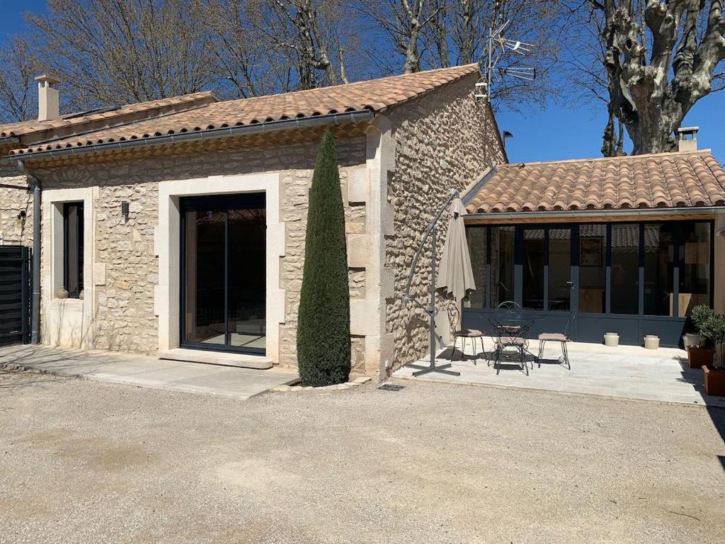 ein Steinhaus mit einem Tisch und einem Sonnenschirm in der Unterkunft Mazet Le Micocoulier in Saint-Rémy-de-Provence