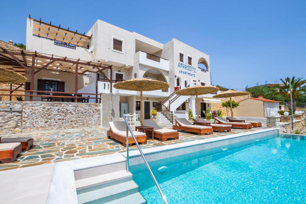 una villa con piscina con sedie e ombrelloni di Aphrodite Luxury Studios & Apartments a Karpathos