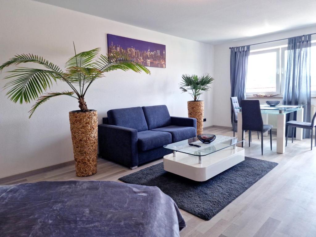ein Wohnzimmer mit einem blauen Sofa und einer Palme in der Unterkunft HappySide BrightLines - Parkplatz - Nespresso - WLAN in Leipzig