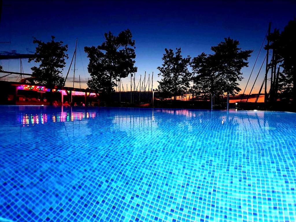 una gran piscina azul por la noche en BL LAKESIDE APARTMAN, en Balatonlelle