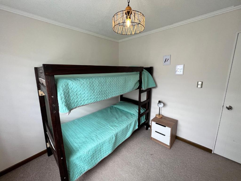 a bedroom with a bunk bed with green sheets at Casa nueva en Pucón in Pucón