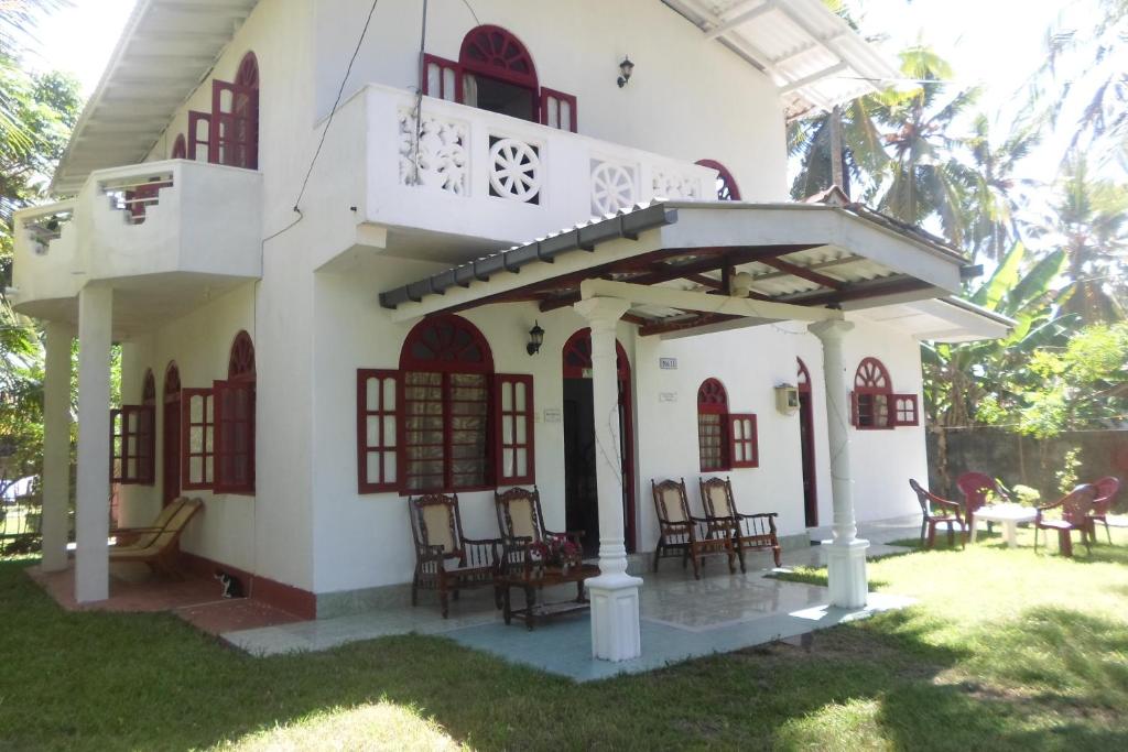 ein Haus mit einem Balkon und Stühlen im Hof in der Unterkunft Raj Villa Kumarakanda Hikkaduwa in Hikkaduwa