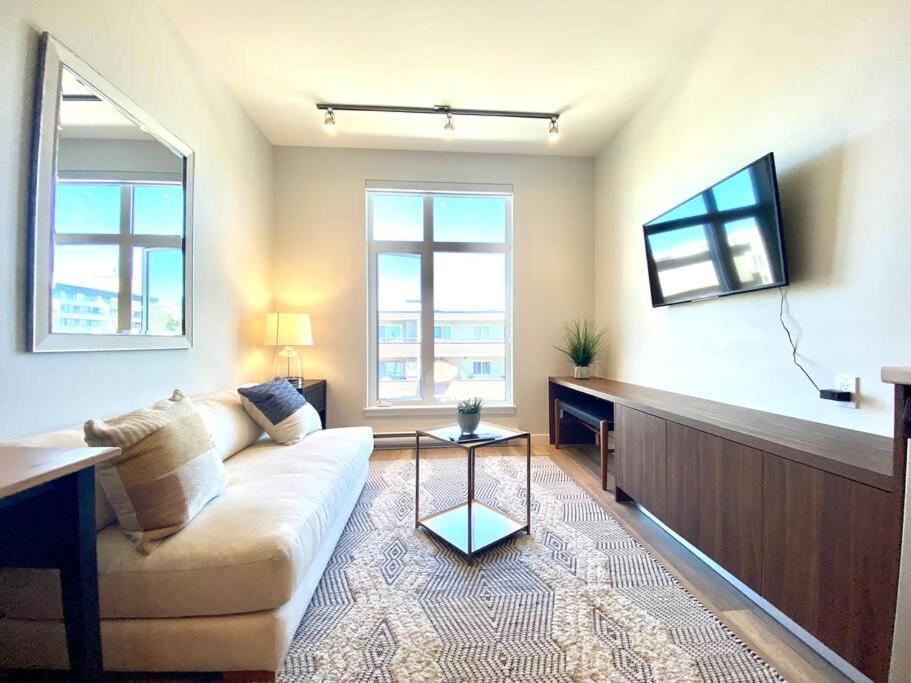 uma sala de estar com um sofá e duas janelas em Lovely Brand New Condo em Sidney