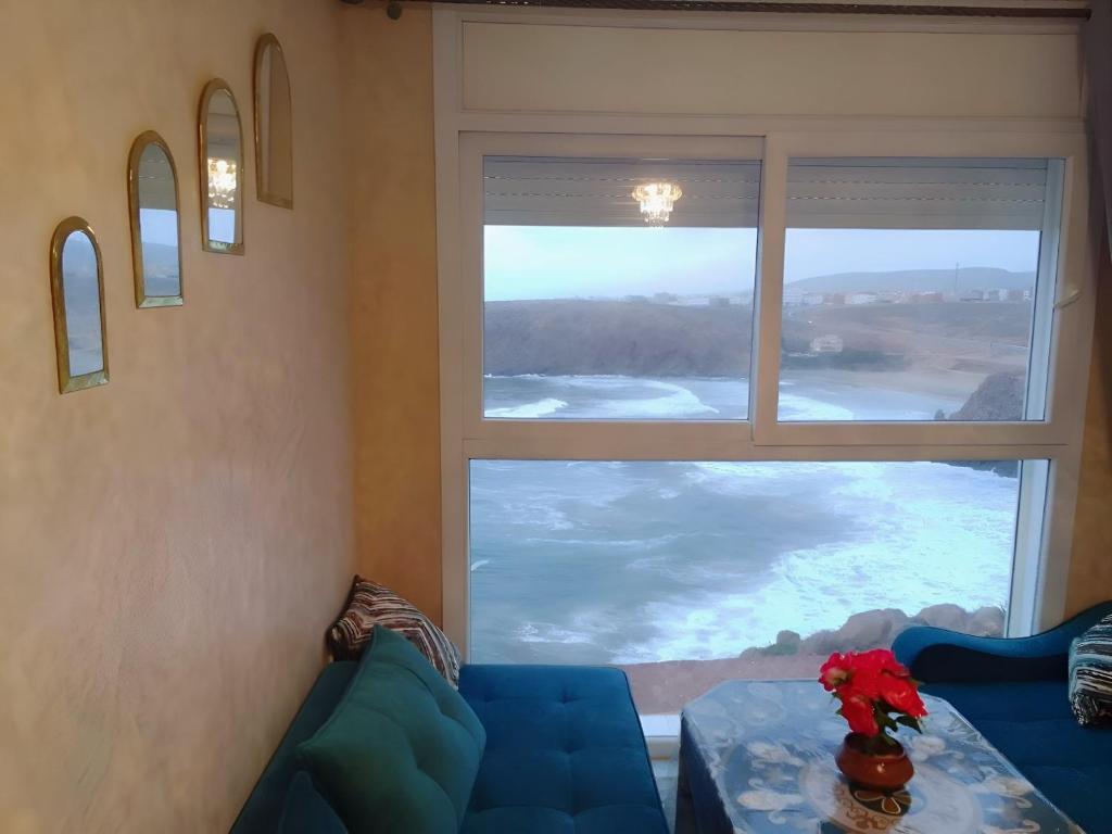 a living room with a blue couch and a large window at Goldenbeachhouse in Mirleft