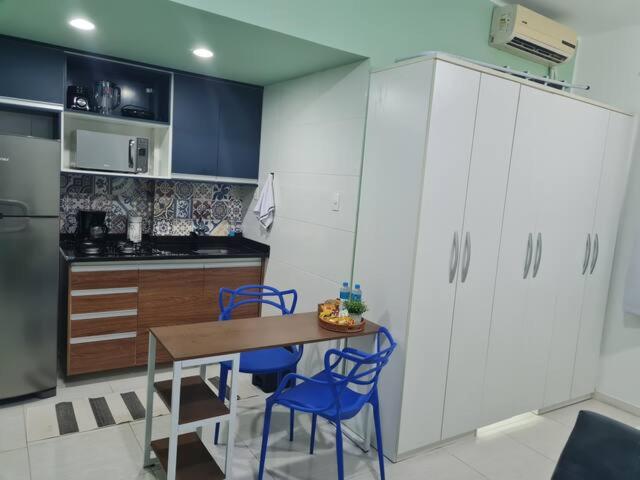 une cuisine avec une table en bois et des chaises bleues dans l'établissement Estúdio 2 min Praia Copacabana - Área Nobre, à Rio de Janeiro