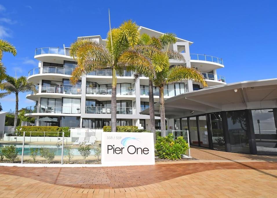 a sign in front of a building with palm trees at Luxurious Beachfront Apartment in Hervey Bay