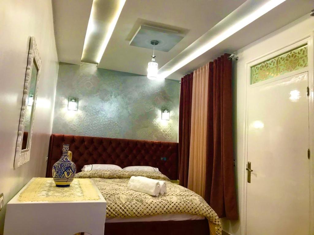 Un dormitorio con una cama y una mesa con un jarrón. en Casa murcia, en Chefchaouen