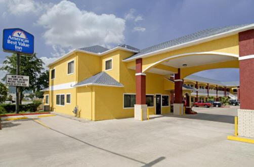 um grande edifício amarelo com um posto de gasolina em Americas Best Value Inn-Baytown em Baytown