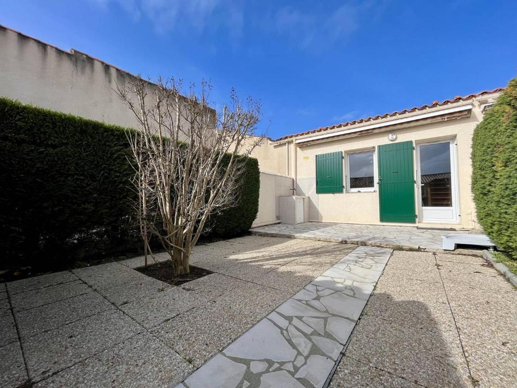 una casa con una puerta verde y un árbol en Maison Dolus-d'Oléron, 2 pièces, 4 personnes - FR-1-246A-236, en Dolus d'Oléron