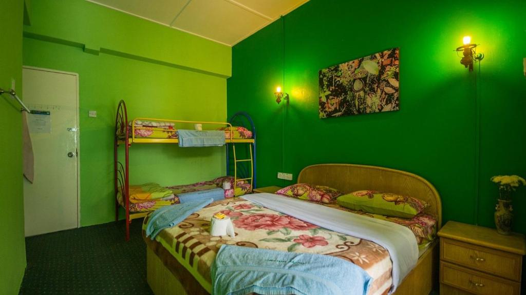 een groene slaapkamer met 2 bedden en een stapelbed bij Rose Haven Hotel in Cameron Highlands