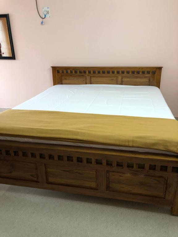 een bed met een houten bedframe in een kamer bij Tirumala Elite Homestay (near Railway station & Bustand) in Tirupati